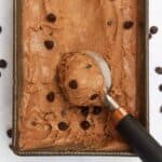 Scooping out some chocolate ice cream with an ice cream scoop from an aluminum tin.