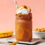 A glass of chickpea milkshake topped with whipped cream and served with a straw.