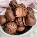 A bowl of chocolate truffles with a pink teacloth beside.