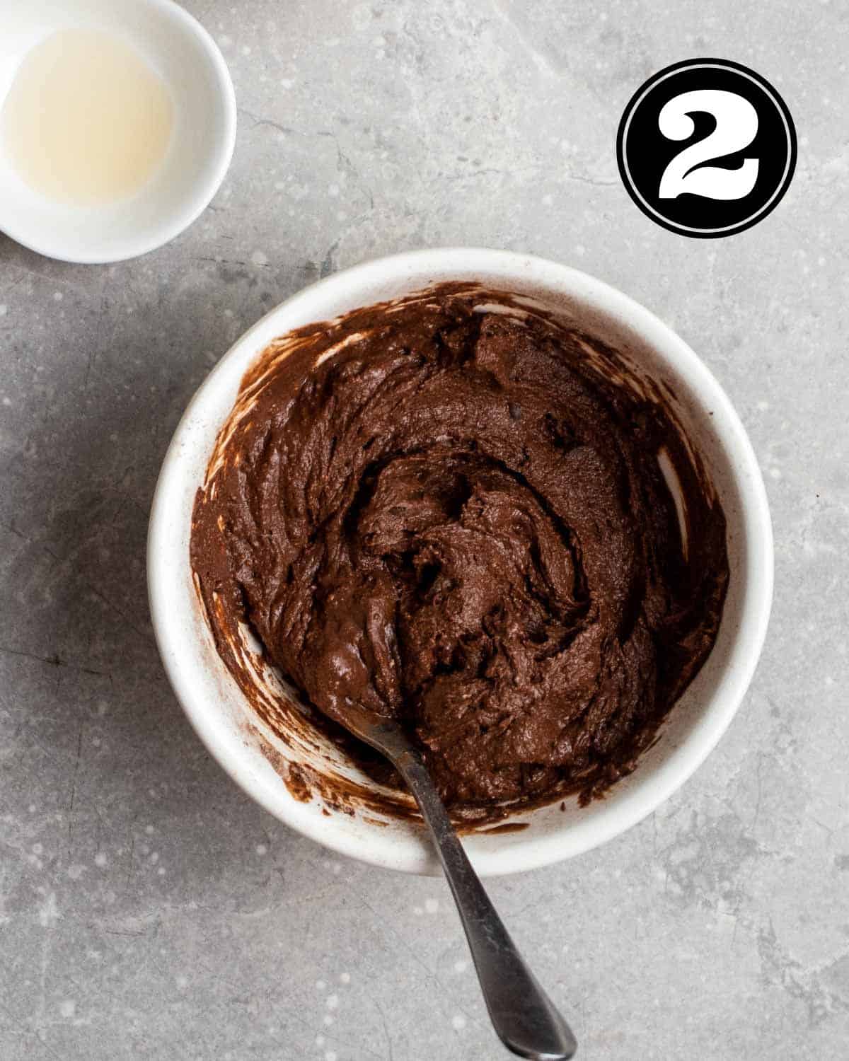 Mug cake batter in a ramekin with a teaspoon beside.