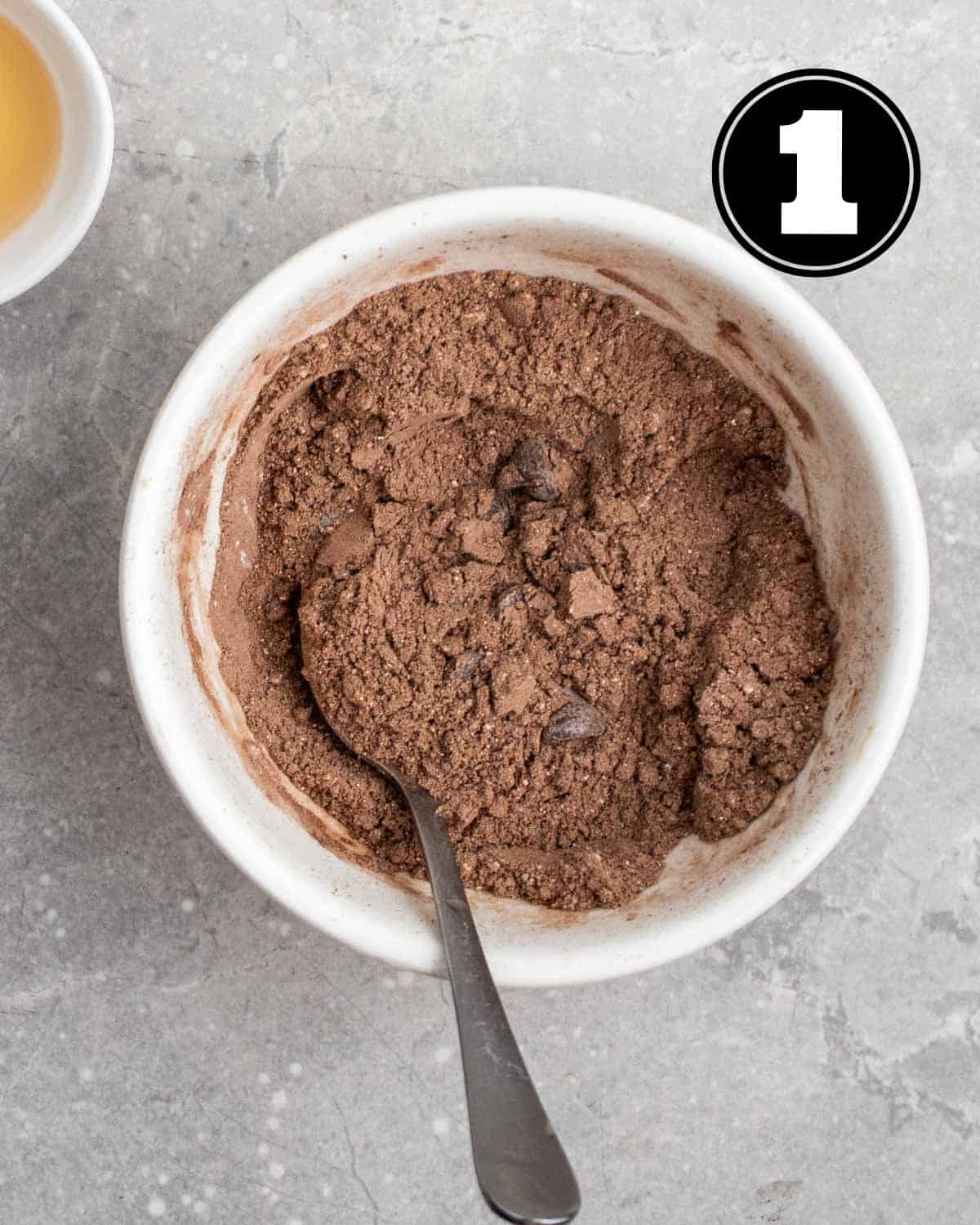 Dry ingredients for mug cake in a ramekin with a teaspoon beside.