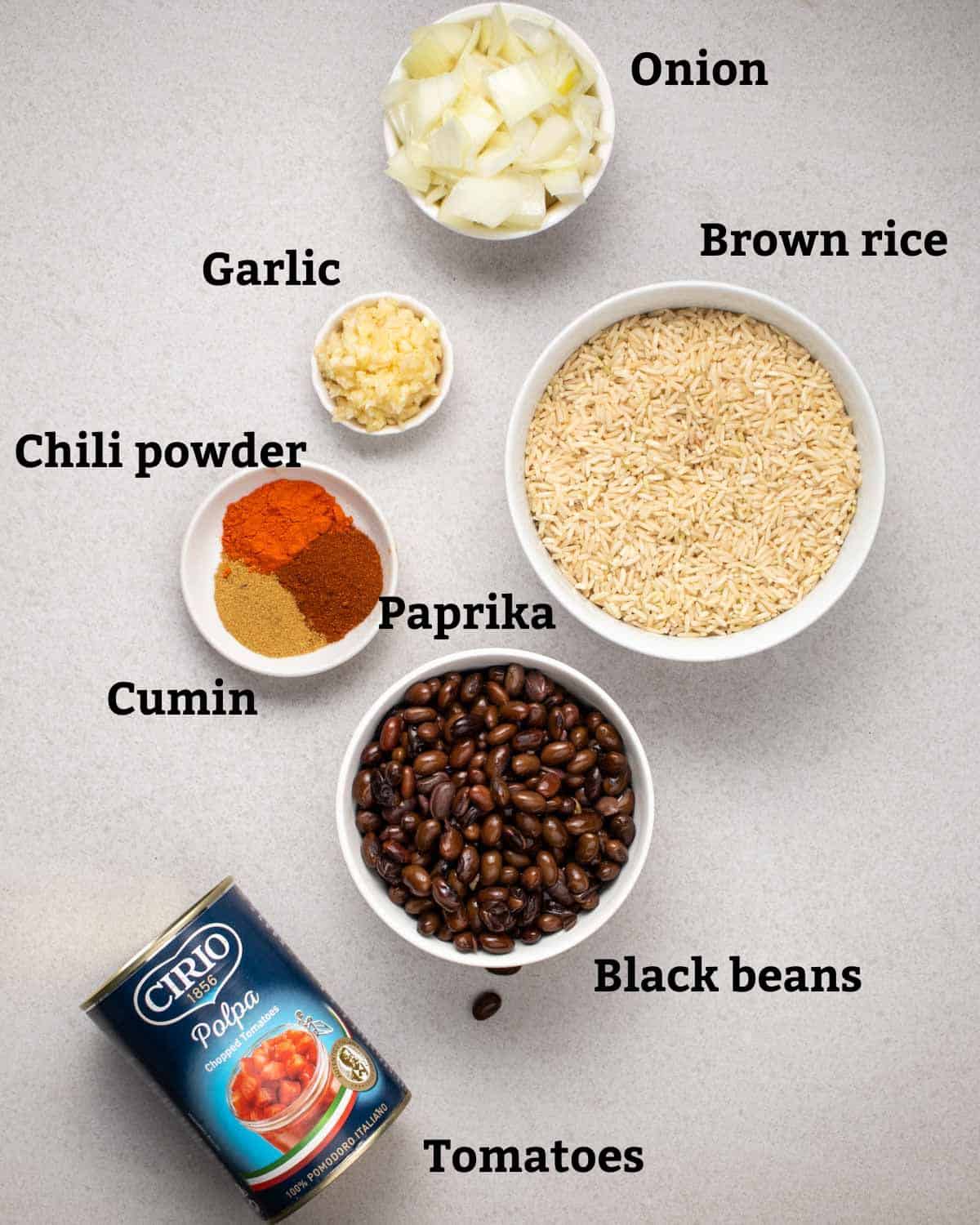 Ingredients needed like onion, garlic, brown rice, spices, black beans, and a can of tomatoes.