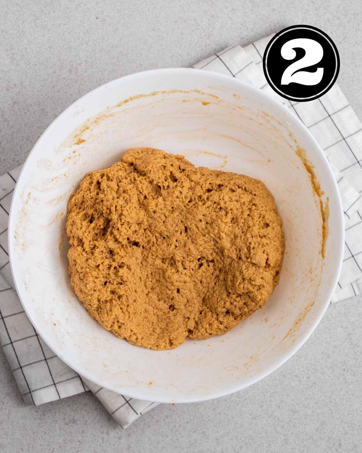 Seitan dough in a white bowl on a white folded teacloth.