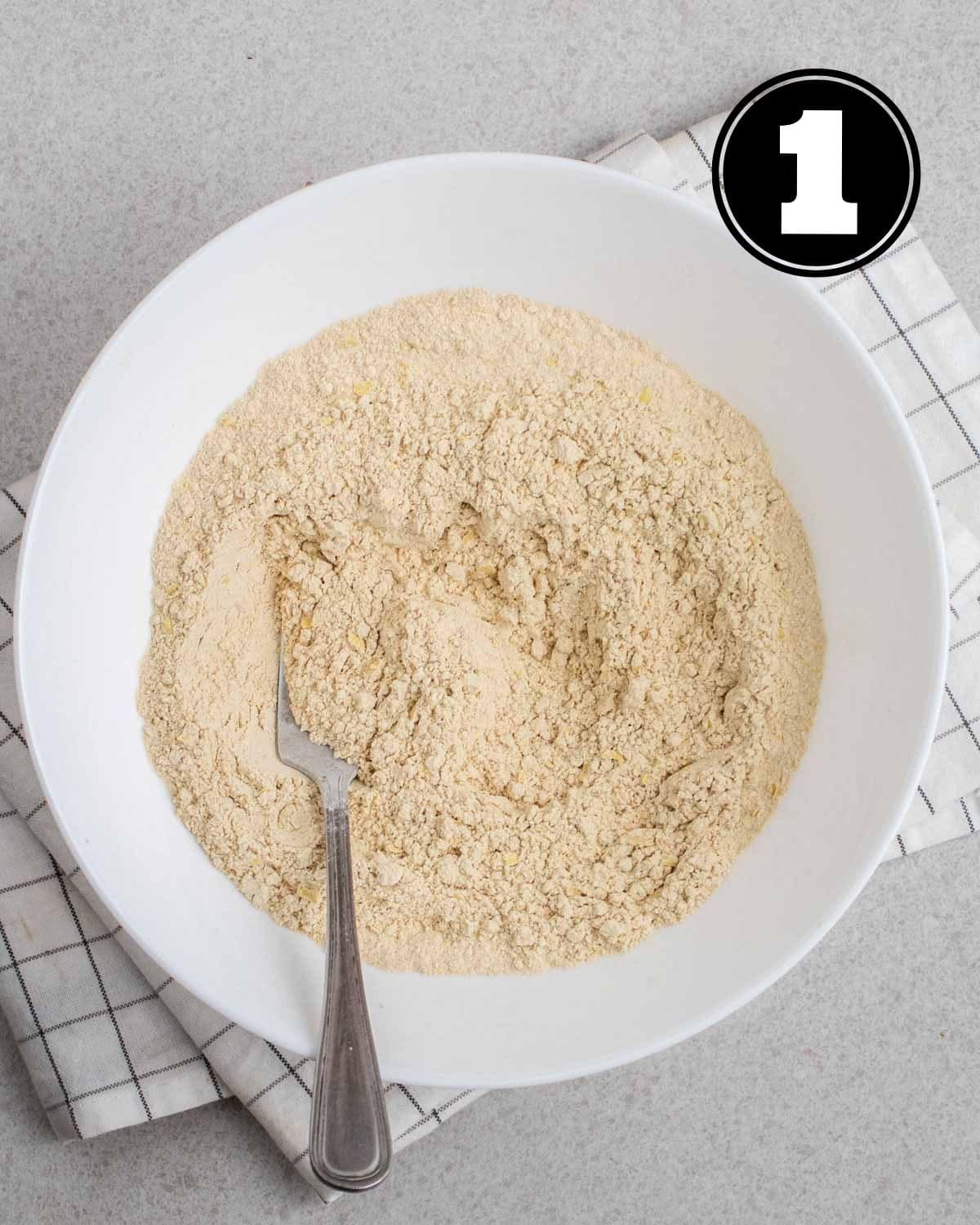Dry ingredients in a bowl with a fork beside.