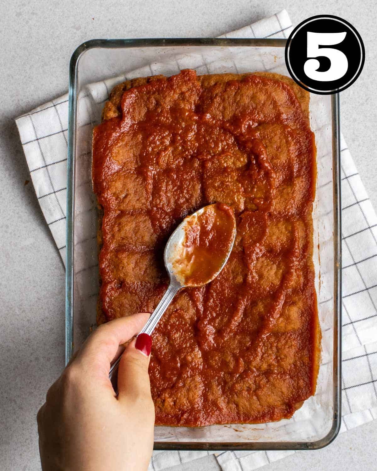 Spreading BBQ sauce on a partially cooked seitan.