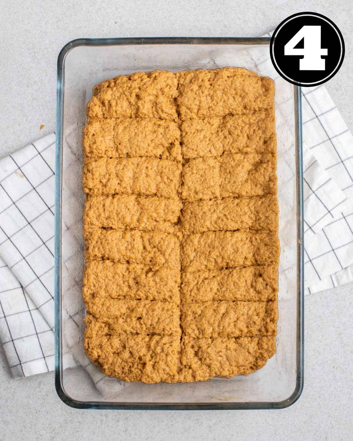 Uncooked seitan ribs in a glass baking pan on a white folded teacloth.