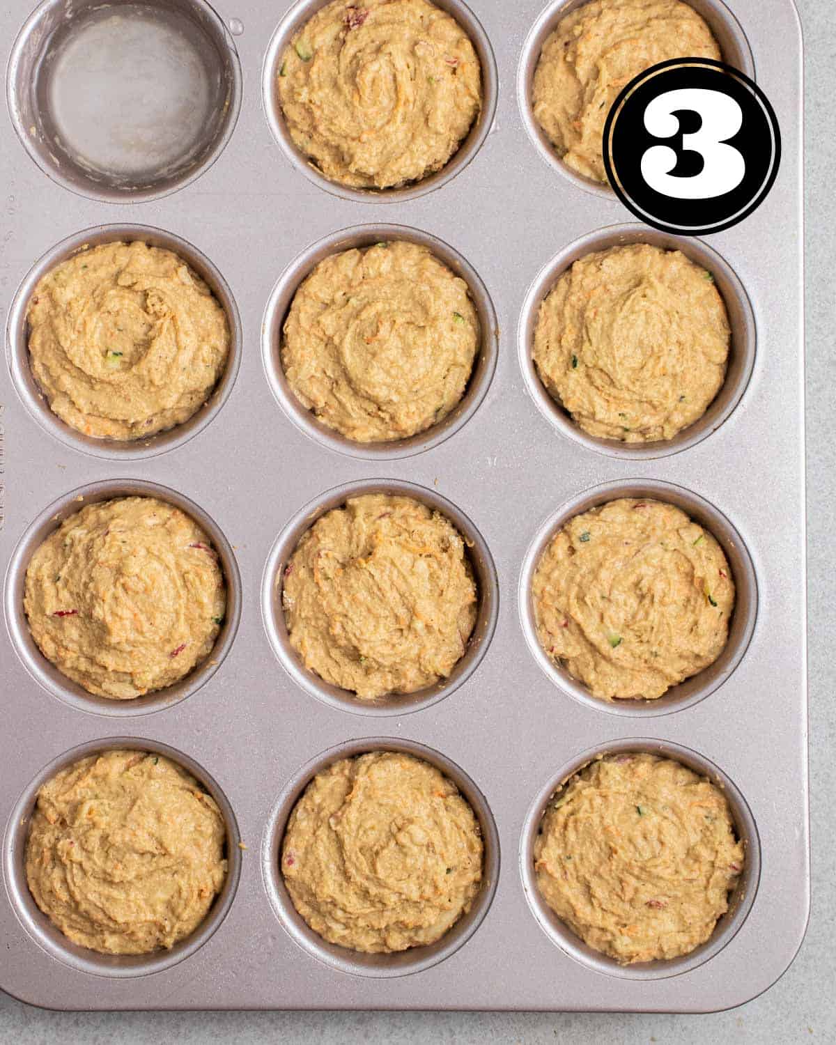 Unbaked muffins in a muffin tray.