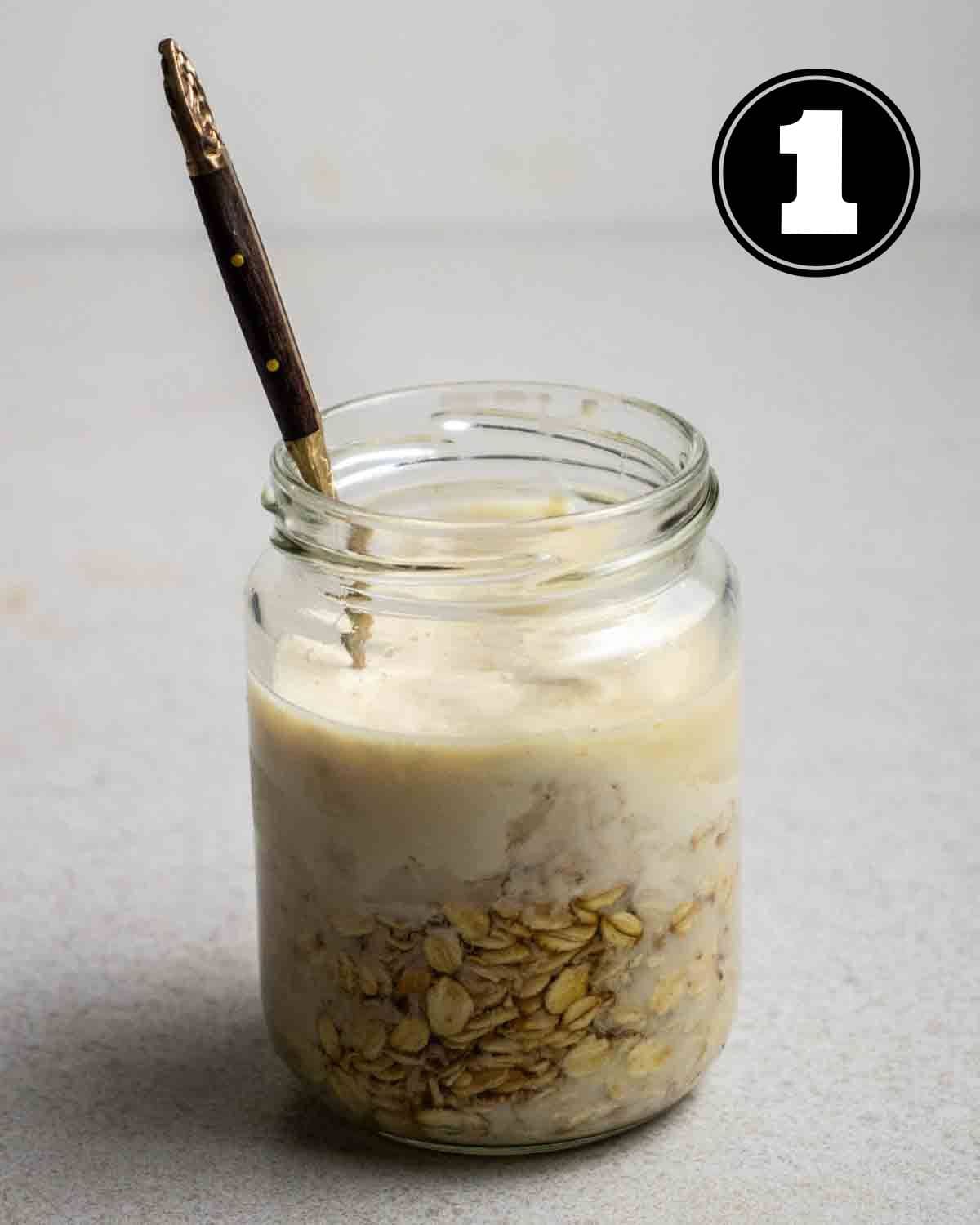 Ingredients for overnight oats in a jar with a spoon beside.