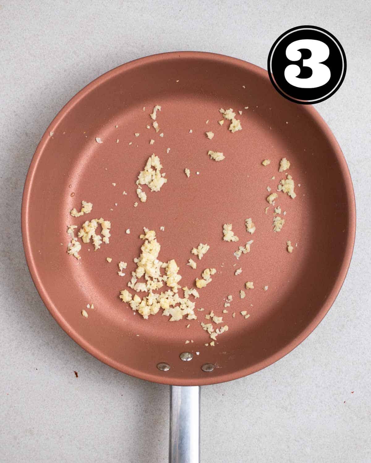 Sauteed ginger and garlic in a pink non-stick pan.