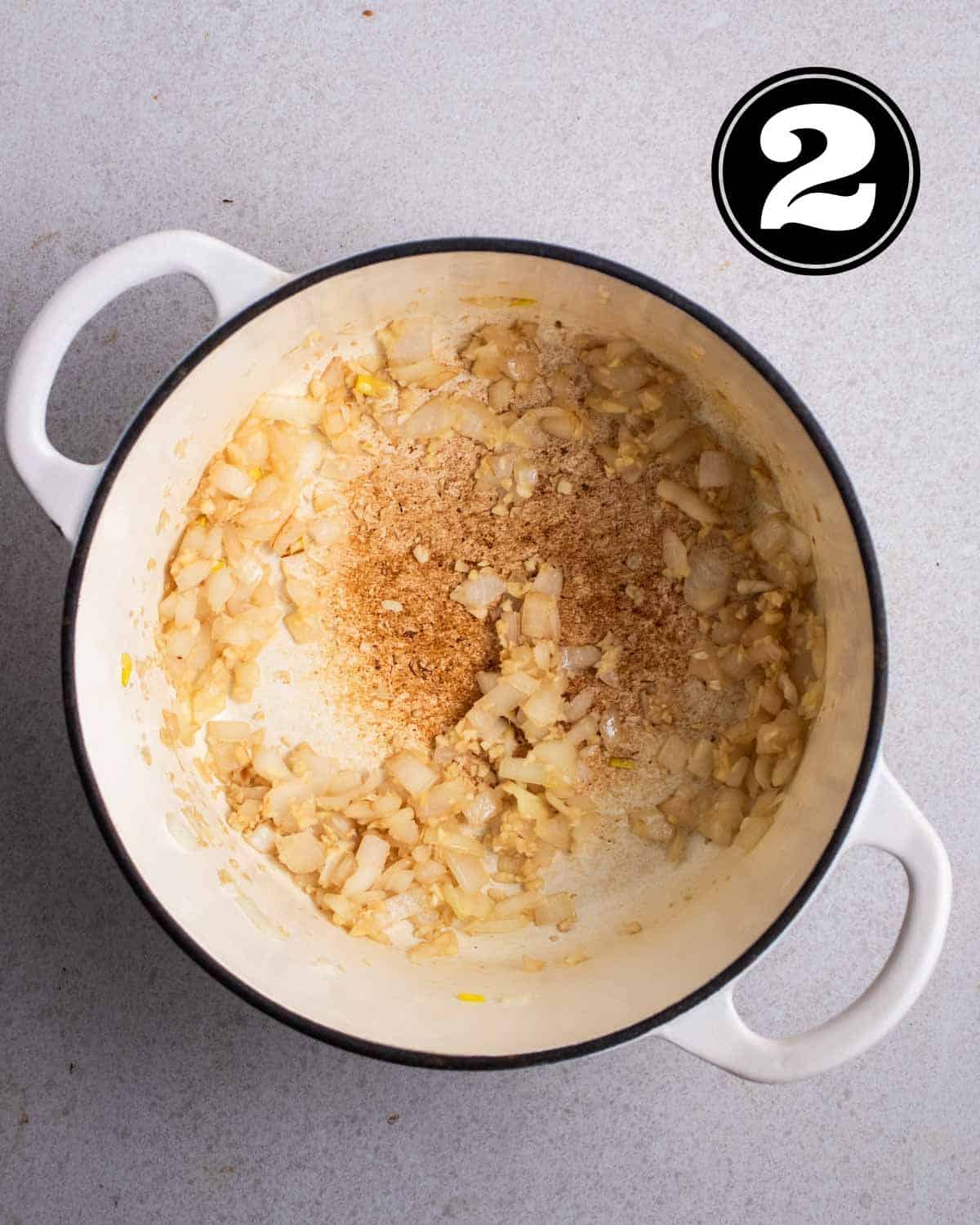 Sauteed garlic and onion in a white Dutch oven.