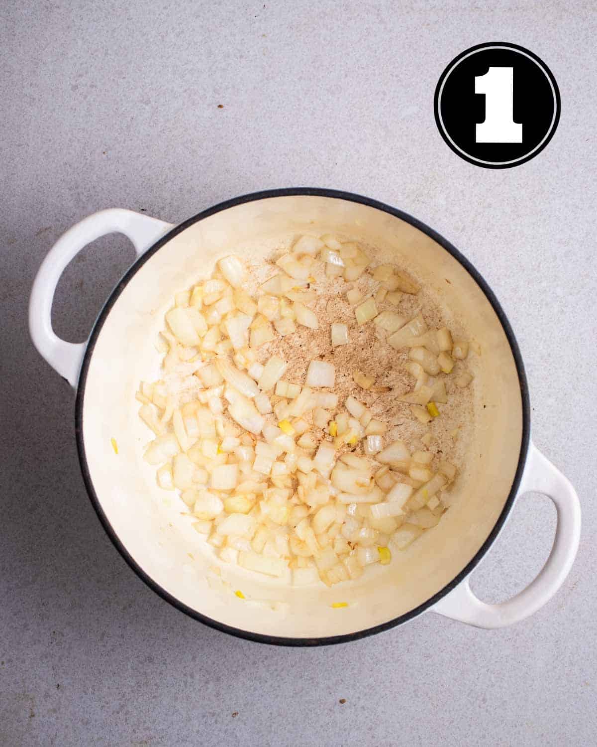 Sauteed onion in a white Dutch oven.