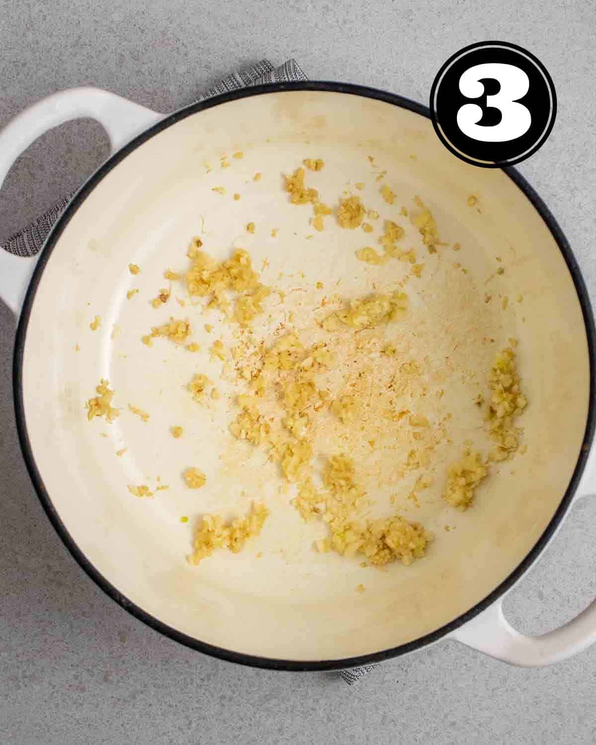Cooked minced ginger and garlic in a white Dutch oven.