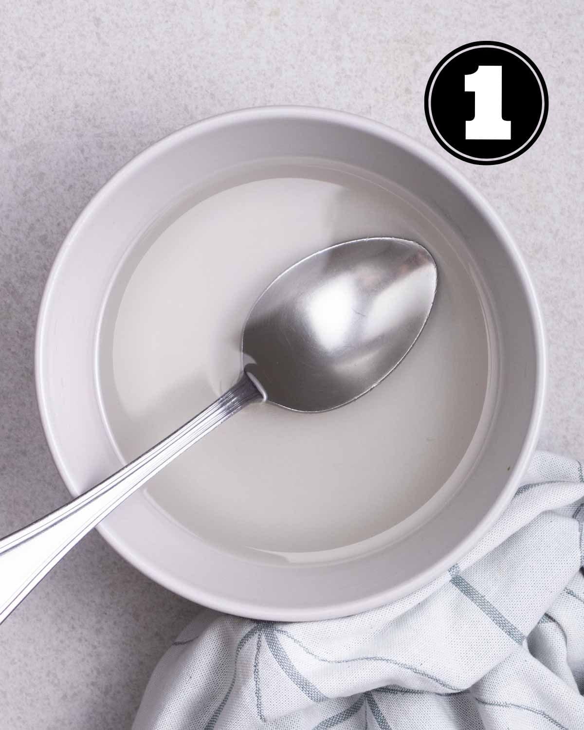 Sugar solution in a bowl with a spoon beside.